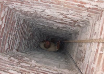 Technician down inside chimney flue with rope hanging down