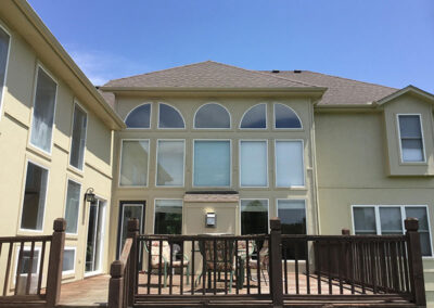 outside a beige house with lots of windows and a deck